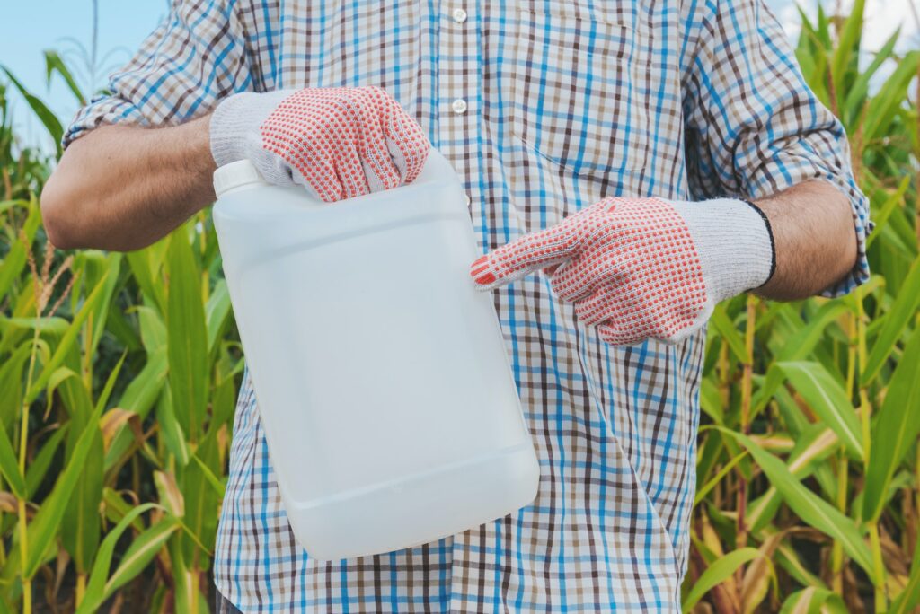 Farmer holding pesticide chemical jug in cornfield